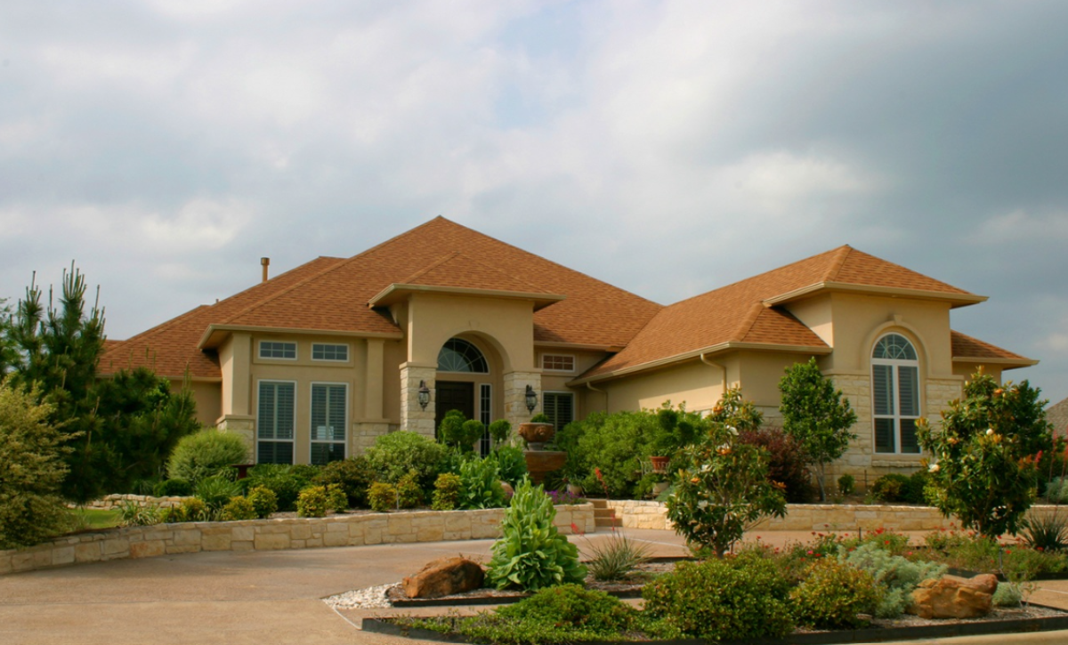 Why is stucco popular in California? modern brick and stucco house with extensive landscaping and plantings in front
