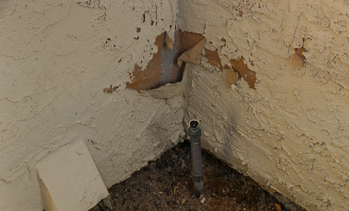 Water-damaged stucco exterior showing cracks, staining, and moisture damage